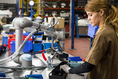图为一名工人和合作机器人在制造工厂工作。